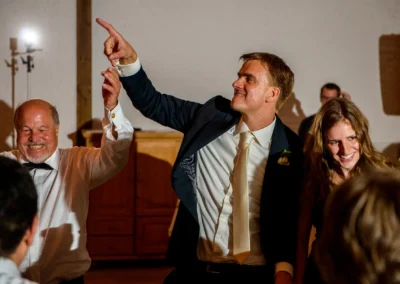 Gruppe von Hochzeitsgaesten tanzt und lacht auf einer Hochzeit in Gut Georgenberg. Hochzeitsreportage in Oberbayern.