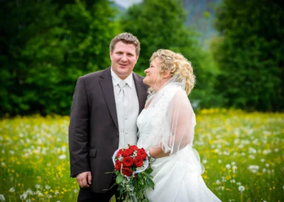 Brautpaar posiert auf Blumenfeld in Kreuth, perfekte Hochzeitsfotosession für natürliche Hochzeitsfotografie in Bayern.