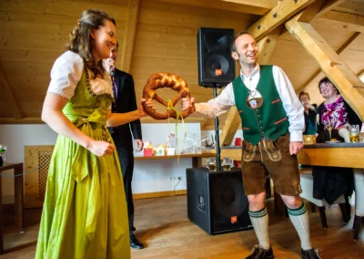 Brautpaar mit Brezel bei Hochzeitsfest im Bio Landhotel Moarwirt. Hochzeitsreportage in traditioneller Tracht.
