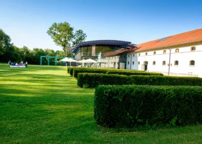 Gruppe auf Rasen bei Hochzeit in Oberbayern, nahe Kloster Fuerstenfeld. Modernes Gebaeude im Hintergrund. Hochzeitsreportage.