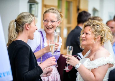 Gäste stoßen mit Sekt bei einer Hochzeit in Kreuth an. Hochzeitsfotografie Momente voller Freude und Gemeinschaft.