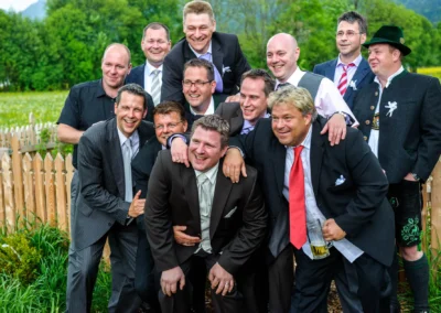 Gruppe lachender Maenner bei Hochzeit in Kreuth am Tegernsee. Hochzeitsfoto von Hochzeitsreportage im Freien.