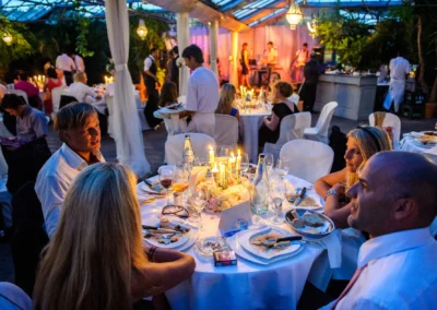 Gedeckter Hochzeitstisch mit Gästen, Kerzen und Liveband im Hintergrund in der Alten Gaertnerei Taufkirchen.
