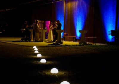 Gartenbeleuchtung bei Nacht auf einer Hochzeit im Gut Schloss Sulzemoos mit beleuchteten Holzwänden im Hintergrund.