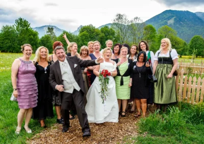 Brautpaar mit Freunden bei einer Hochzeitsreportage in Kreuth am Tegernsee, fröhliche Stimmung im Grünen.