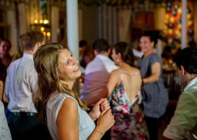 Lachende Hochzeitsgaeste tanzen in Aufkirchen, festgehalten von einem Hochzeitsfotografen nahe Starnberger See.