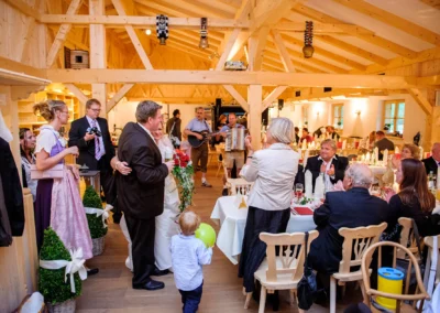 Gesellschaft bei einer Hochzeit in Kreuth am Tegernsee, mit Musikern und festlich gedeckten Tischen. Hochzeitsfotografie.