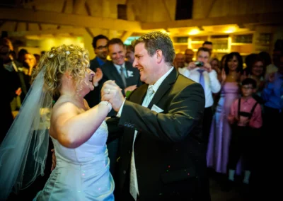 Brautpaar tanzt auf Hochzeit in Kreuth am Tegernsee, umgeben von lachenden Gaesten. Hochzeitsreportage in Bayern.