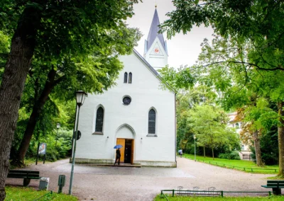 Kirchliche Trauung in Muenchen, stilvolle Kirche umgeben von Baeumen. Hochzeitsfotograf dokumentiert den besonderen Tag.
