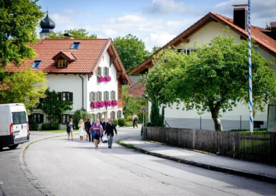 Gruppenspaziergang auf einer Straße in Bernried nach einer standesamtlichen Trauung, umgeben von traditionellen Häusern.