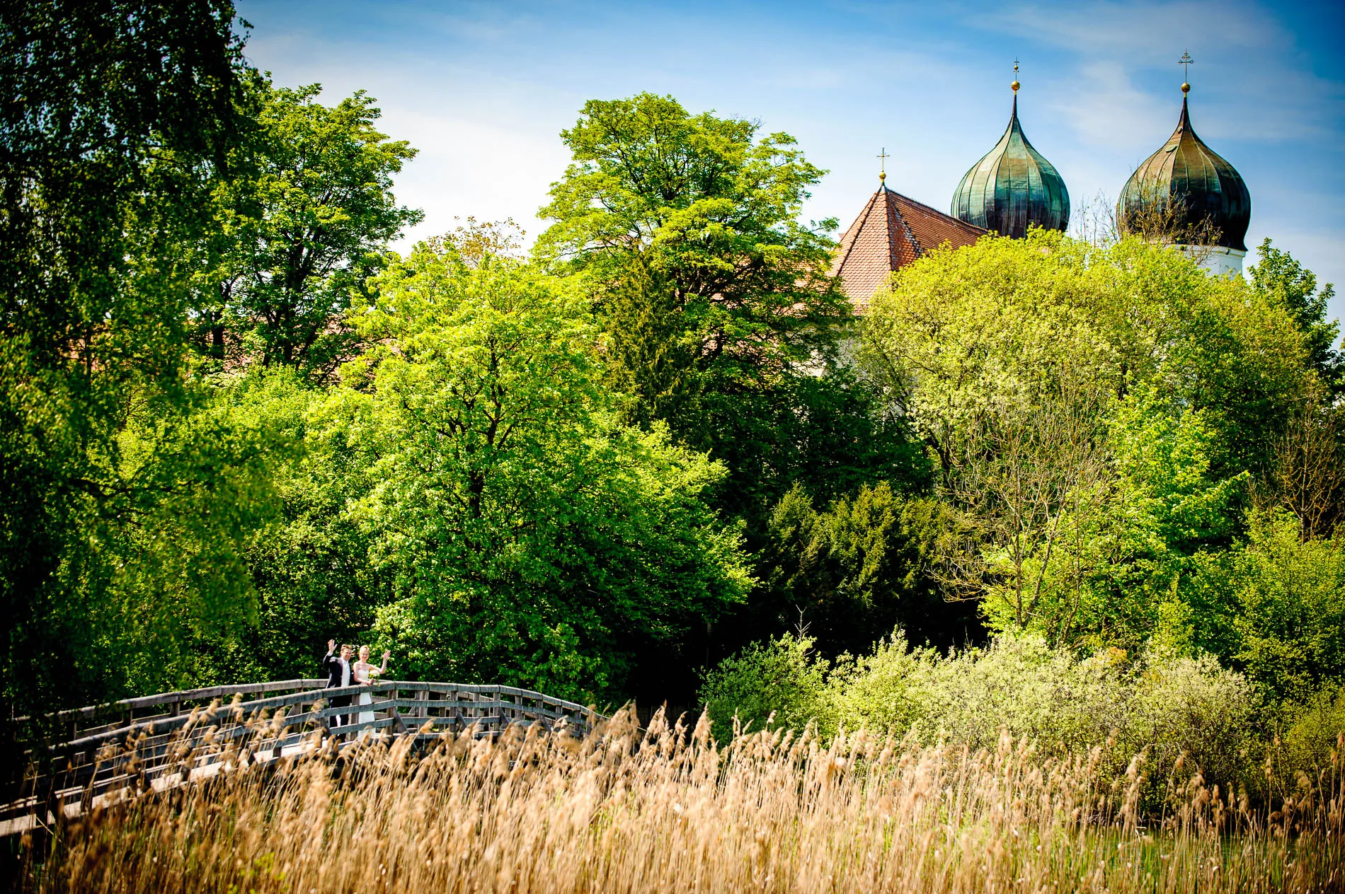 Brautpaar auf Holzbruecke im Gruen nahe Kloster Seeon im Chiemgau, Hochzeitsfotografie in Oberbayern nahe des Chiemsees.