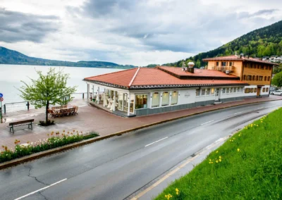 Cafe Kreutzkamm am Tegernsee bei bewölktem Himmel. Aufnahme zeigt Hochzeitlocation mit See im Hintergrund.
