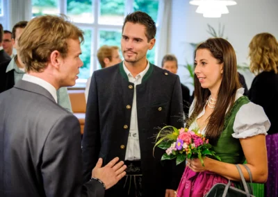 Gespraech waehrend standesamtlicher Trauung in Muenchen. Traditionelle Kleidung und bunte Blumenstraeusse.