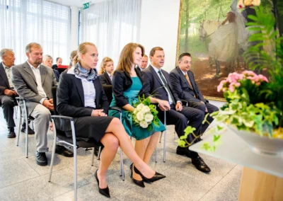 Gäste bei einer standesamtlichen Trauung in Pasing, München. Elegante Hochzeitsfotografie mit Blumenarrangement im Vordergrund.