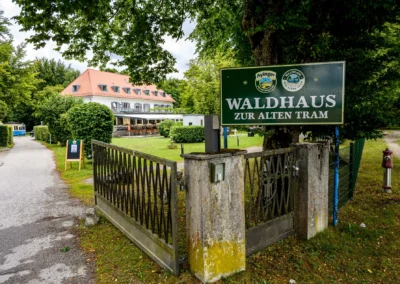 Hochzeitslocation Waldhaus zur Alten Tram bei Muenchen, Gartenansicht mit Eingangstor und Beschilderung.