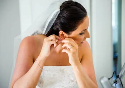 Braut steckt Ohrringe an, Hochzeitsvorbereitung in Aufkirchen, Hochzeitsfotografie Oberbayern.