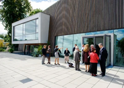 Menschen versammelt vor modernem Gebaude bei einer standesamtlichen Hochzeit in Bernried am See. Hochzeitsreportage.