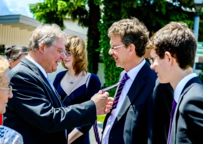 Gesellschaft lacht und unterhalt sich in Anzugen bei einer Hochzeit in Garmisch-Partenkirchen im Freien.