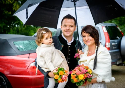 Familie bei standesamtlicher Trauung mit Regenschirm und Blumenstrauss, aufgenommen am Standesamt Herrsching.
