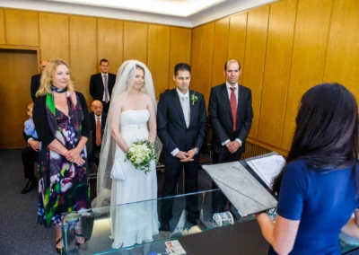Brautpaar bei standesamtlicher Trauung in Muenchen Schwabing, Braut in Hochzeitskleid, Begleiter und Standesbeamtin.