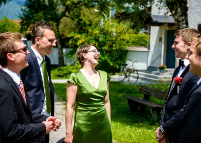 Gruppe von Gaesten lacht im Freien bei einer Hochzeitsreportage in Oberbayern.