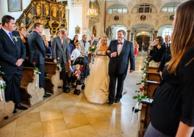 Braut schreitet zur Kirche bei Trauung Kloster Benediktbeuern. Hochzeitsfotografen-Moment eingefangen.