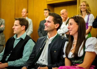 Gäste bei standesamtlicher Trauung in München, lächeln in traditioneller Kleidung. Hochzeitsfotografie im Standesamt.