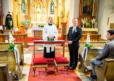 Kirchliche Trauung in Pasing: Der Priester steht mit dem Bräutigam vor dem Altar in einer geschmückten Kirche.