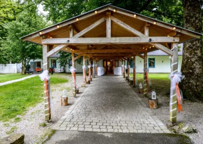 Hochzeitslocation mit geschmücktem Holzdach und Kiesweg bei Gruenwald, ideal für Hochzeitsfotografie im Gruenwalder Forst.