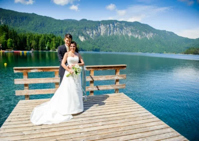 Brautpaar auf Steg am Eibsee bei Hochzeitsfoto, umgeben von Bergen und Wasser in malerischer Landschaft nahe Garmisch.