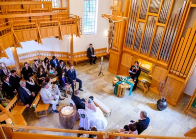 Kirchliche Trauung in Murnau mit Brautpaar und Gaesten in der Kirche, aufgenommen von Hochzeitsfotograf.