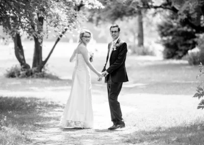 Brautpaar bei Hochzeitsreportage im Park von Muenchen, romantischer Spaziergang Hand in Hand.