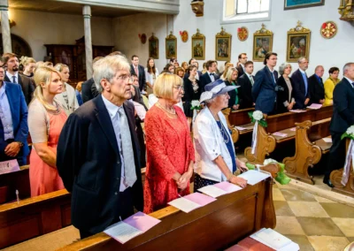 Gaste stehen in einer Kirche zur kirchlichen Trauung nahe Tegernsee, Teil einer Hochzeitsreportage.