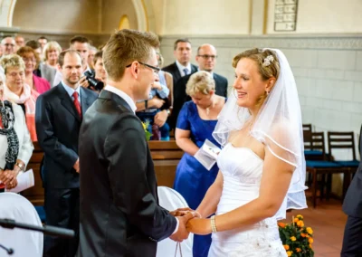Brautpaar bei kirchlicher Trauung in der evangelischen Friedenskirche, Hochzeitsfoto mit Gaesten im Hintergrund.