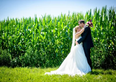 Brautpaar umarmt sich vor einem Maisfeld bei Taufkirchen. Romantische Hochzeitsfotografie im Freien.