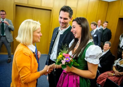 Brautpaar bei standesamtlicher Trauung in München, Gratulation einer Dame im Dirndl, Hochzeitsreportage.