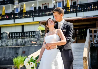 Brautpaar posiert vor Eibsee Hotel, lachend und haltend. Aufnahme bei einer Hochzeit nahe Garmisch.