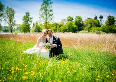Hochzeitspaar auf Wiese nahe Kloster Seeon im Chiemgau, romantische Hochzeitsfotos vor idyllischer Kulisse.