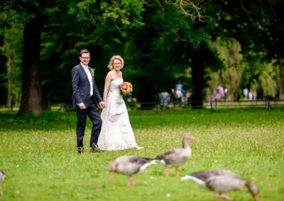 Brautpaar im Englischen Garten Muenchen bei der Hochzeitsfotografie, umgeben von Baeumen und Wiesen.