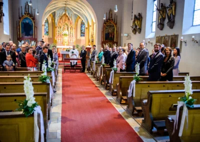Kirchliche Trauung in Pasing: Gäste stehen in einer geschmückten Kirche. Hochzeitsfotografie aus München.
