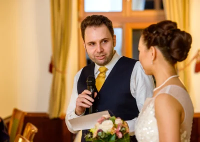 Ein Mann mit Mikrofon spricht zu einer Braut bei einer Hochzeit nahe Schliersee. Hochzeitsfotografie im Fokus.
