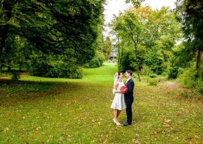 Brautpaar auf grüner Wiese bei Hotel Kaiserin Elisabeth am Starnberger See. Hochzeitsportrait mit Blumen.