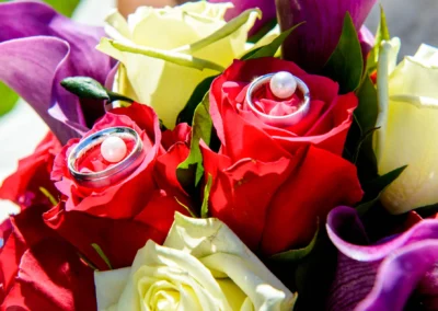 Nahaufnahme von roten und gelben Rosen mit Eheringen bei einer Hochzeit nahe Muenchen.