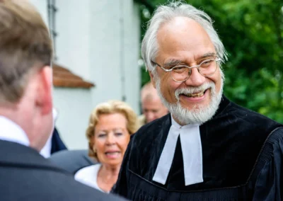 Lachender Pfarrer bei kirchlicher Trauung auf Hochzeit in Gut Thurnsberg, noerdlich von Muenchen.