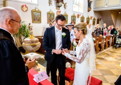 Brautpaar tauscht Ringe während kirchlicher Trauung in Waakirchen. Hochzeitsreportage von einem Hochzeitsfotograf.