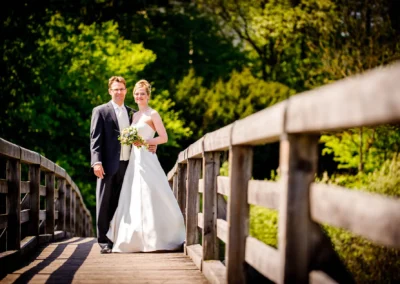 Brautpaar auf Holzbruecke im Gruenen, Hochzeitsportrait bei Kloster Seeon im Chiemgau, Hochzeitsfotografie.