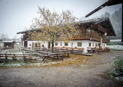 Winterliche Hochzeitslocation im Wasmeier Museum mit schneebedecktem Baum und bayerischem Gebaude.