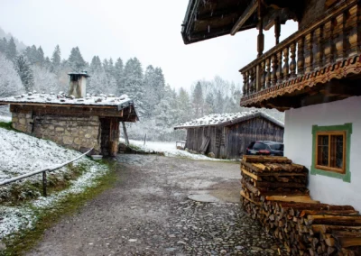 Winterlich verschneite Hochzeitslocation im Wasmeier Freilichtmuseum Schliersee, rustikale Holzhaeuser und Stapel.