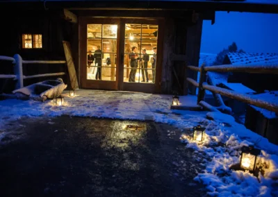 Winterliche Hochzeit im Wasmeier Freilichtmuseum, beleuchteter Eingang mit Blick auf die feiernde Gesellschaft drinnen.