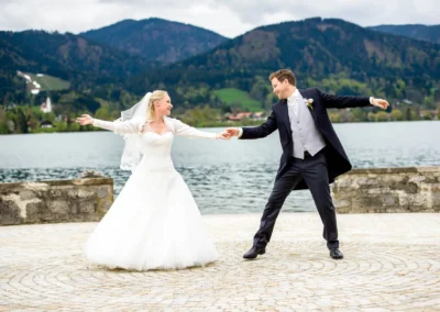 Brautpaar tanzt vor Alpenkulisse am Tegernsee, romantische Hochzeitsfotografie im Freien, aufnahmemitts eines Hochzeitsfotografen.